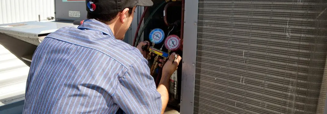HVAC technician servicing a condenser unit in San Pablo